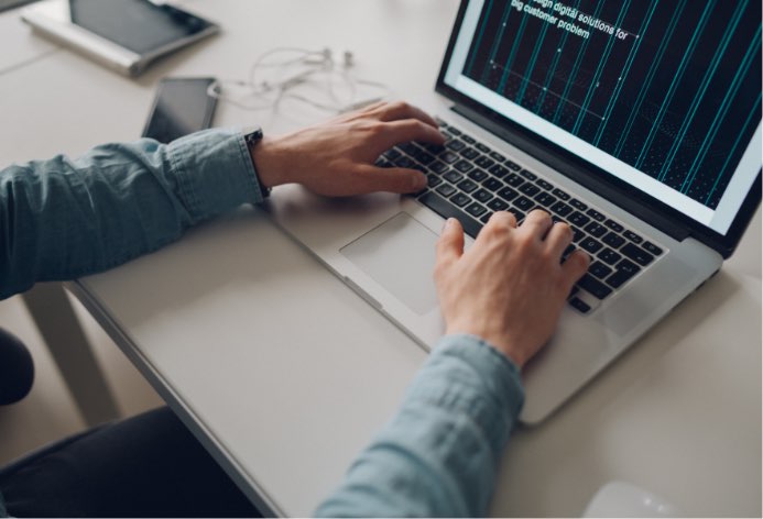 A person working at a desk on there open laptop