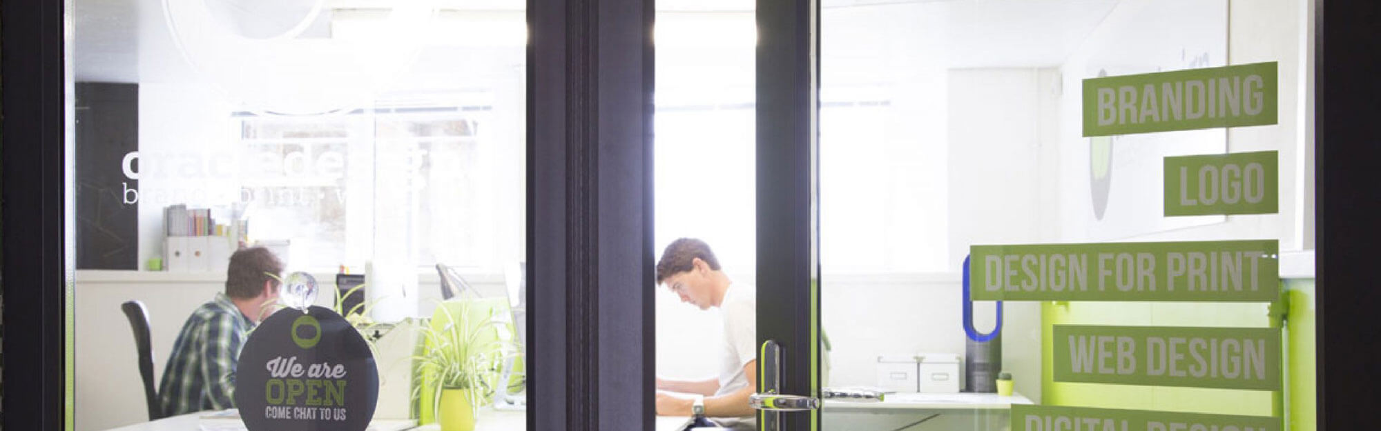 Looking through the windows of the Oracle Design office with 2 people working inside